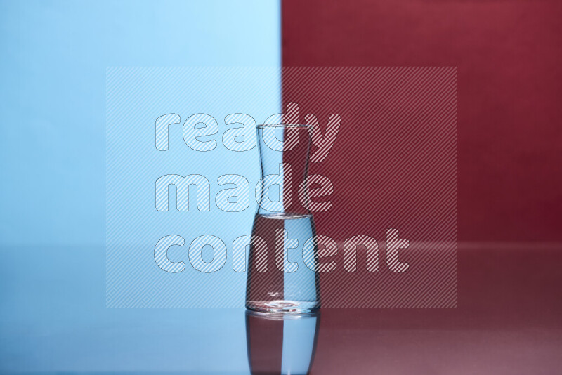 The image features a clear glassware filled with water, set against light blue and dark red background