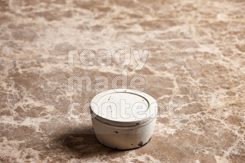 A white pottery bowl on beige marble background