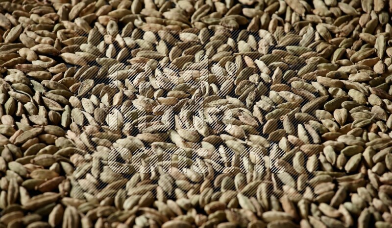 Cardamom seeds filling the frame on black flooring