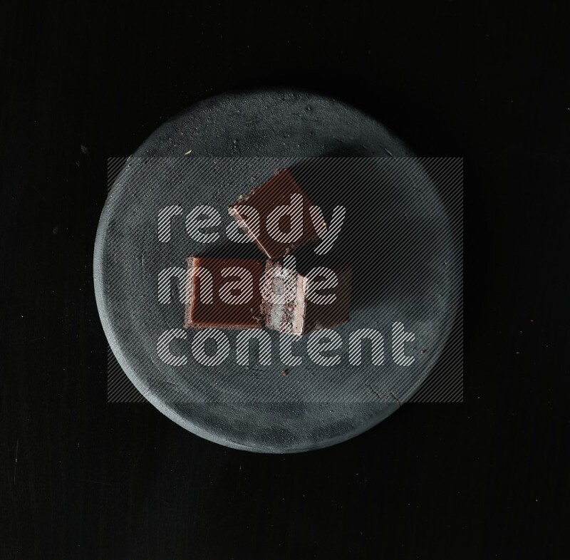 Assorted desserts in a black pottery plate on black background