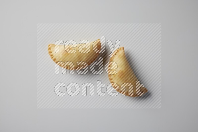 Two fried sambosa from a top angle on a white background