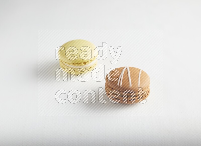 45º Shot of of two assorted Brown Irish Cream, and Yellow Lime macarons on white background