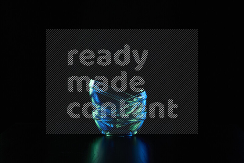 Glassware with rim light in blue and green against black background