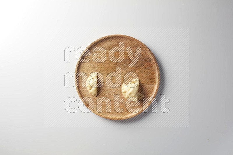 Three Sambosas on a wooden round plate on a white background