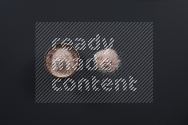 Pottery bowl full of fine himalayan salt and coarse himalayan salt on black background
