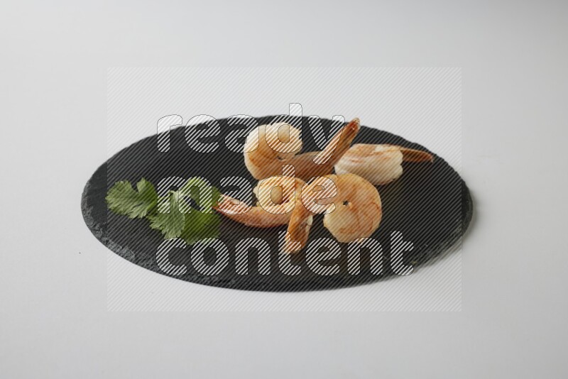four grilled shrimp  on a black slate direct  on a white back ground
