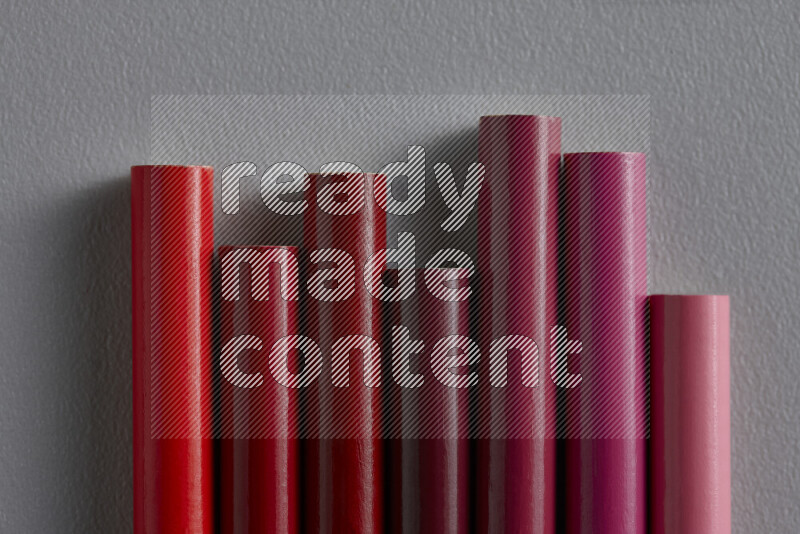 مجموعة من أقلام الرصاص الملونة مرتبة لتعرض تدرجا من اللون الوردي والأحمر علي خلفية رمادية