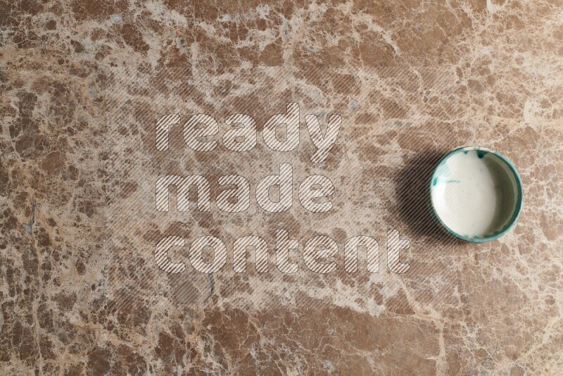 وعاء فخاري متعدد الألوان على خلفية من الرخام البيج