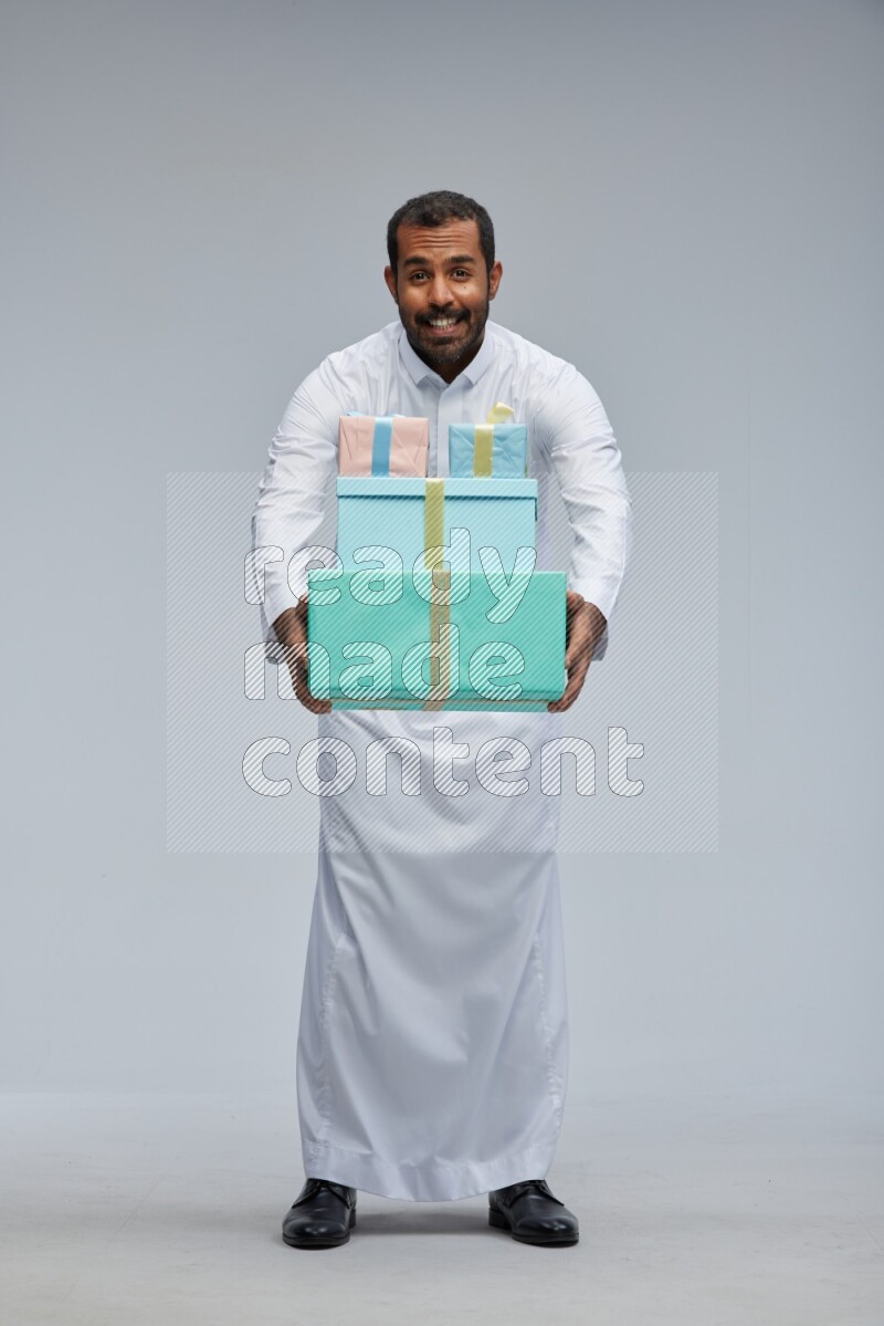 Saudi man Wearing thob standing holding gift box on Gray background