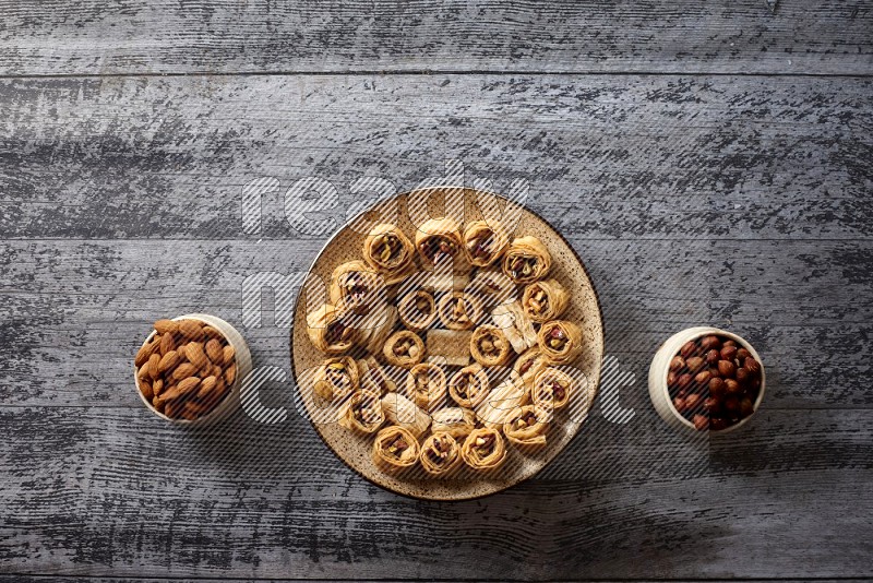 Oriental sweets in a pottery plate with nuts, coffee and honey in a dark setup