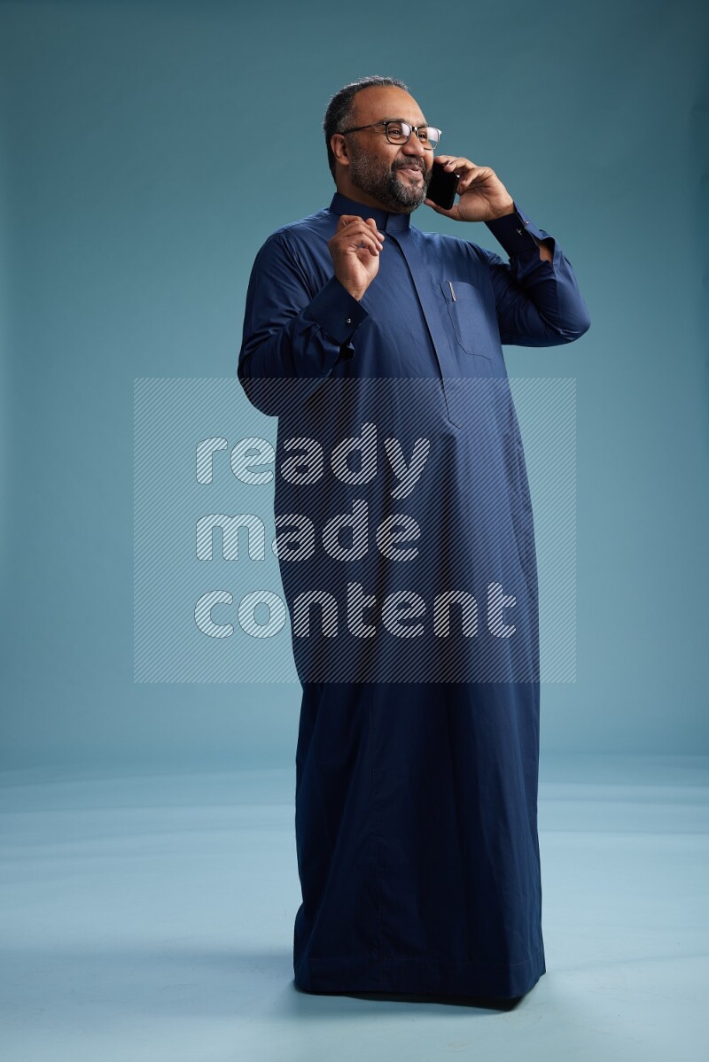 Saudi Man without shimag Standing talking on phone on blue background