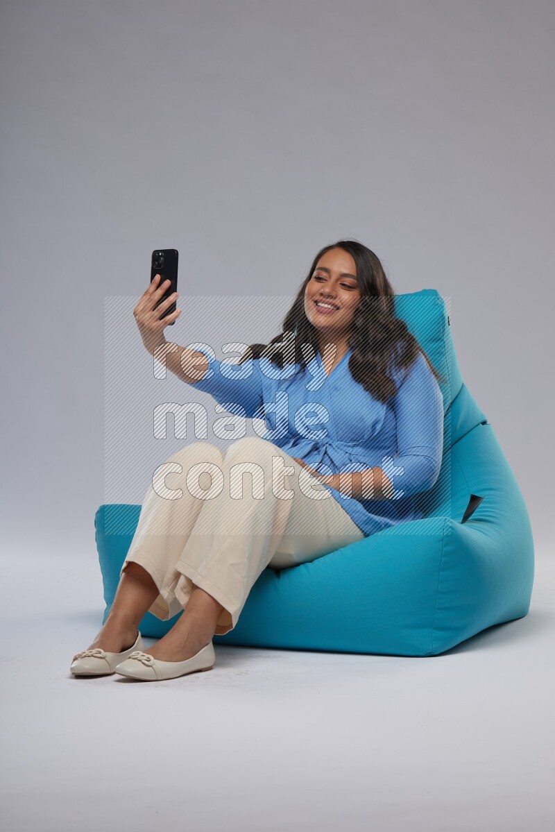 A woman sitting on a blue beanbag and taking selfie