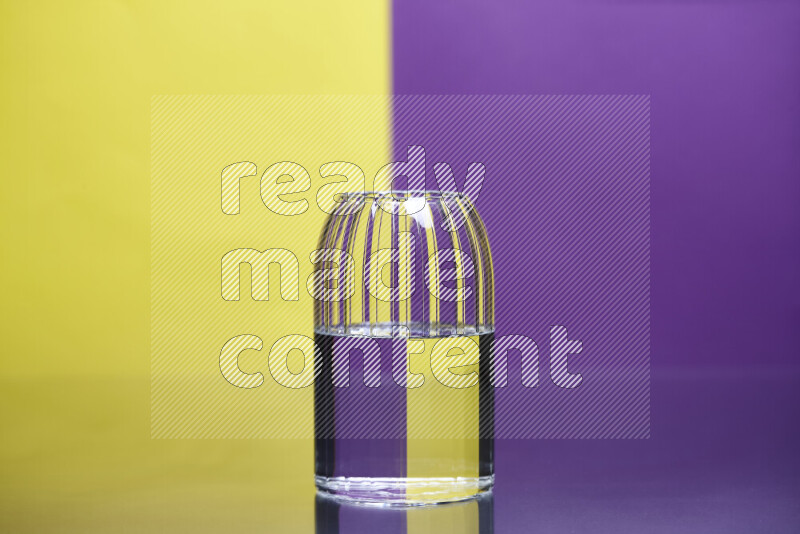 The image features a clear glassware filled with water, set against yellow and purple background
