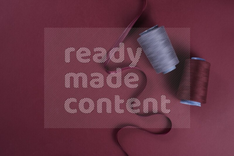 A grey collection of sewing and tailoring tools arranged on a red background