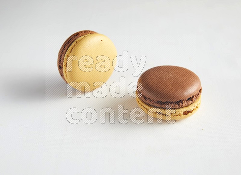 45º Shot of two Yellow and Brown Chai Latte macarons on white background