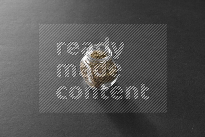 كمون في وعاء زجاجي علي خلفية سوداء