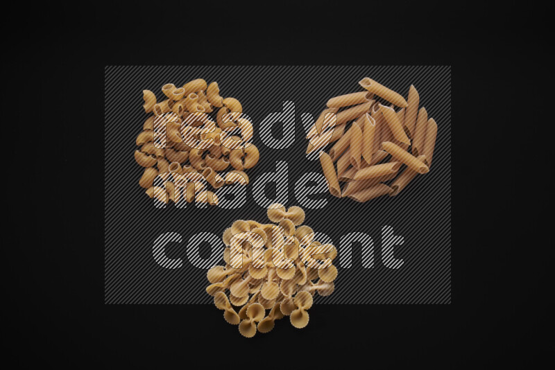 Different pasta types in bunches on black background