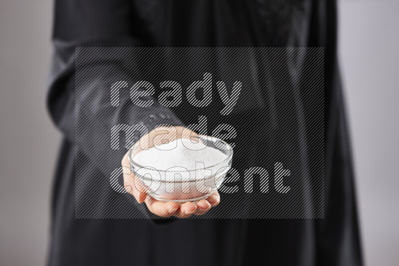 Woman in abaya holding different kinds of spices in different positions