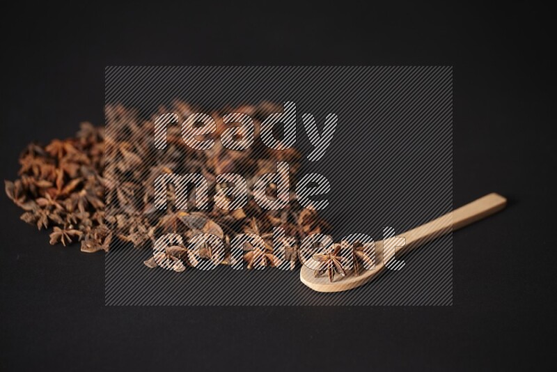 Star Anise in a wooden spoon and spreading on a black flooring