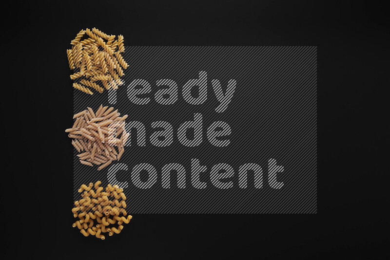 Different pasta types in 3 bunches on black background