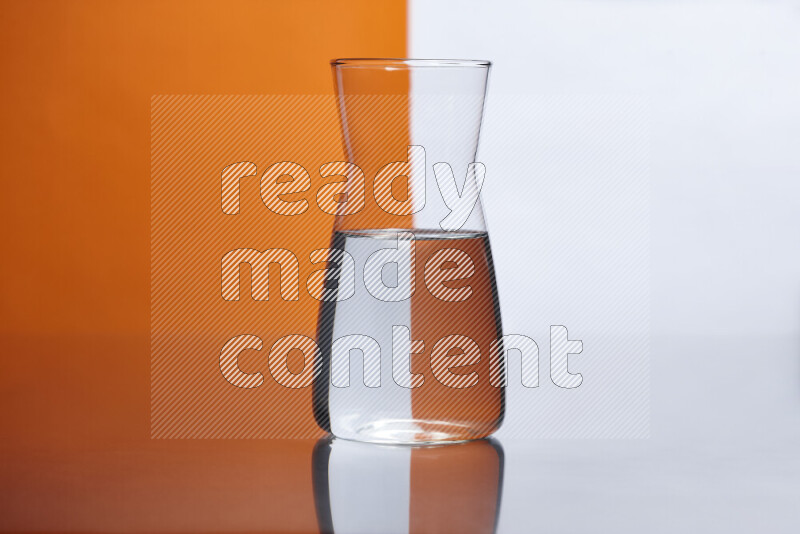 The image features a clear glassware filled with water, set against white and orange background