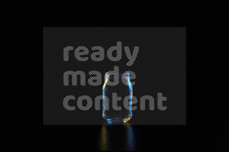 Glassware with rim light in blue and yellow against black background