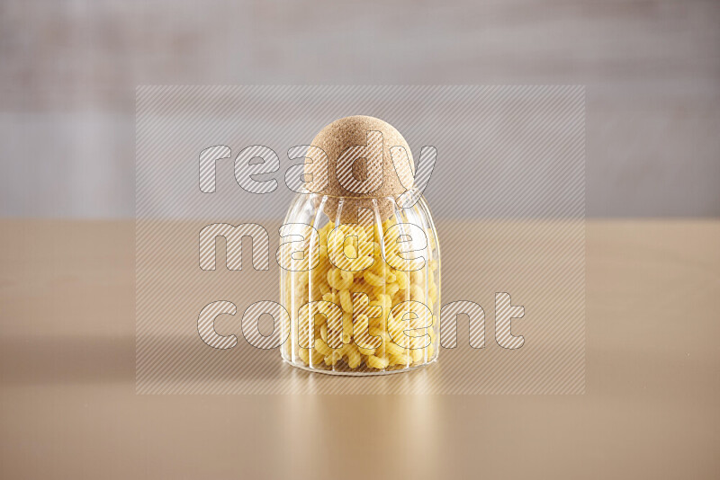 Raw pasta in glass jars on beige background
