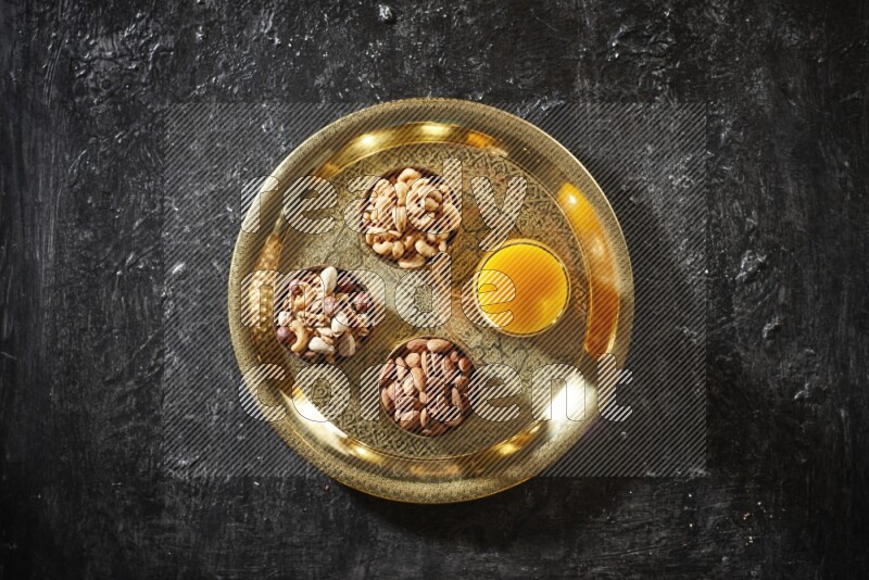 مكسرات في أطباق معدنية مع مشروب قمر الدين على صينية علي خلفية سوداء