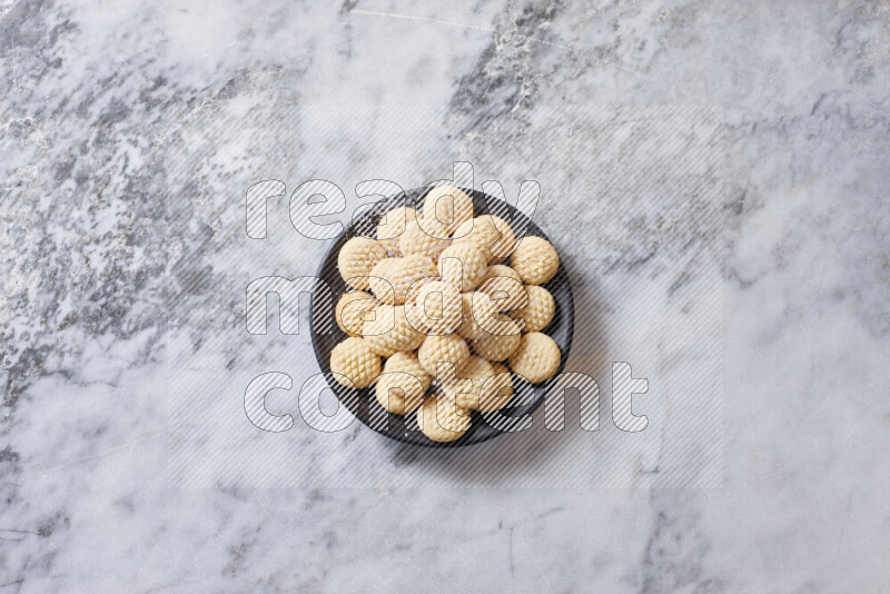 كحك في صحن فخار أسود على خلفية رخام رمادي