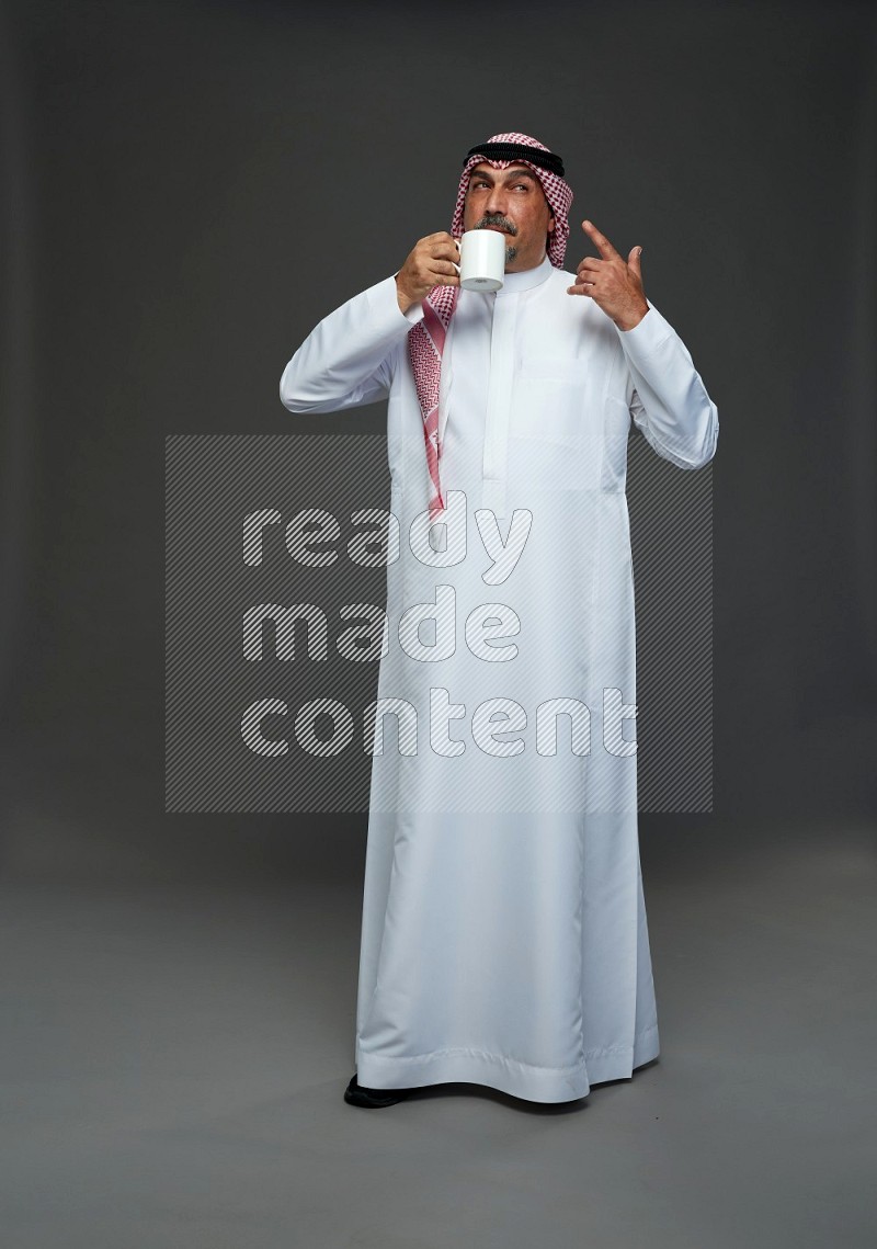 Saudi man with shomag Standing holding mug on gray background