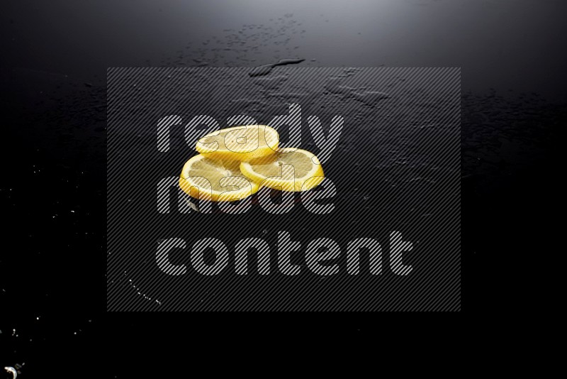 Lemon slices with water drops, and droplets on black background