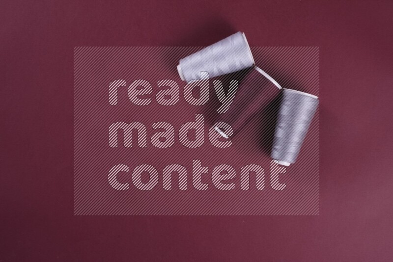 A grey collection of sewing and tailoring tools arranged on a red background