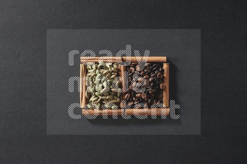 مربعان من أعواد القرفة ممتلئان بحبوب القهوة وحبوب الهيل علي خلفية سوداء