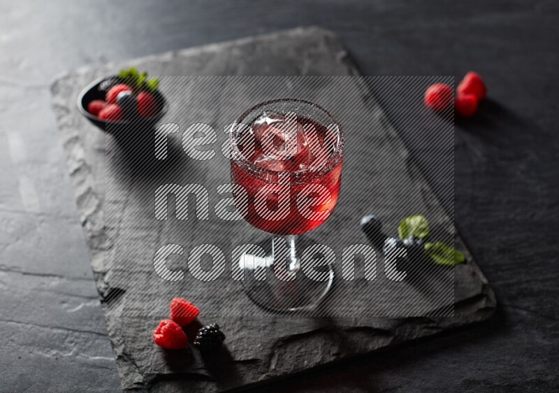 A glass of mixed berries juice on black background