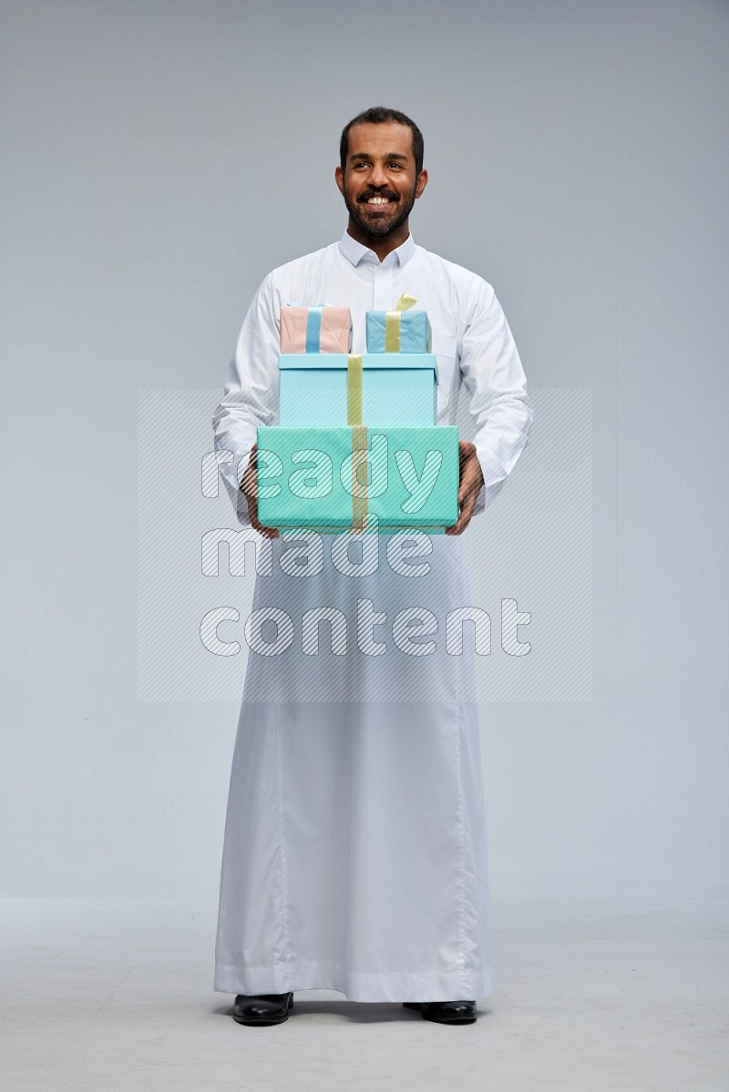 Saudi man Wearing thob standing holding gift box on Gray background