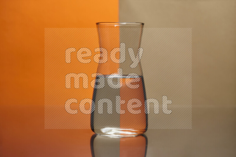 The image features a clear glassware filled with water, set against orange and beige background