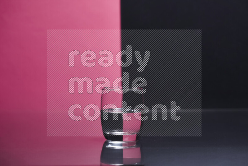 The image features a clear glassware filled with water, set against pink and black background