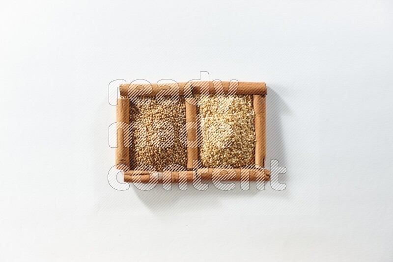 مربعان من أعواد القرفة ممتلئان بحبوب الخردل وبذور السمسم علي خلفية بيضاء