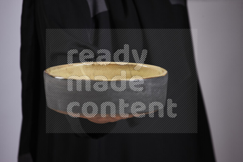 A woman in black abaya holding different pottery essentials in different positions