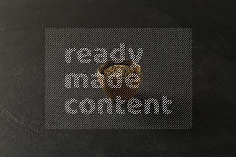 wooden round sauce bowl filled with herbs on grey textured countertop