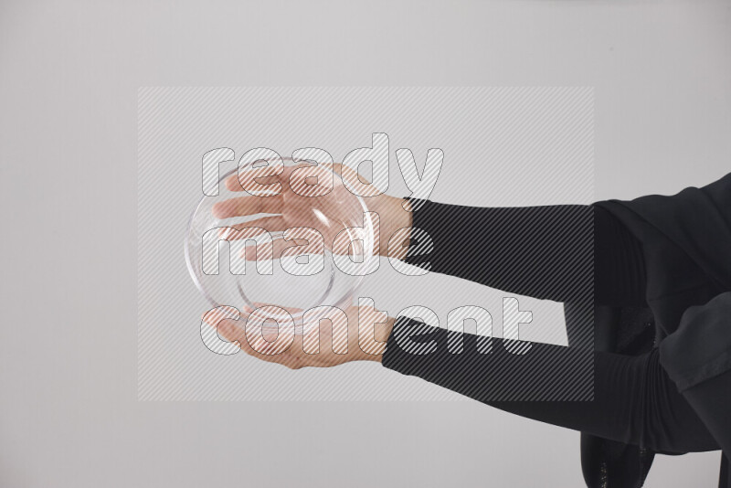 A woman in black abaya holding different glassware in different positions