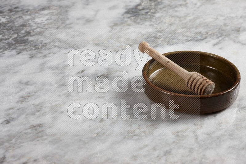 Multicolored Pottery Oven Plate with wooden honey handle in it, on grey marble flooring, 45 degree angel