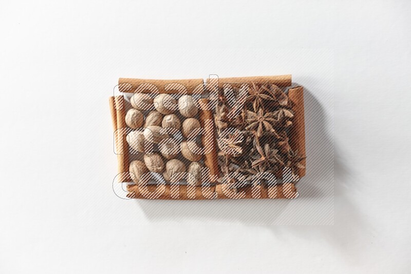 مربعان من أعواد القرفة ممتلئان باليانسون النجمي وجوزة الطيب علي خلفية بيضاء