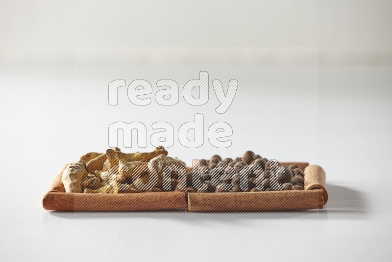 2 squares of cinnamon sticks full of allspice and turmeric fingers on white flooring