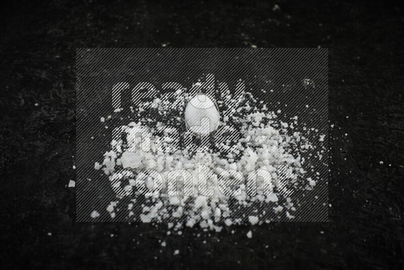 ملعقتان معدنيتان ممتلئتان بالملح الأبيض على خلفية سوداء