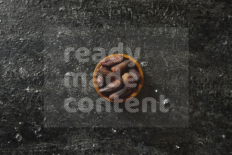 Dates in wooden bowls in a dark setup