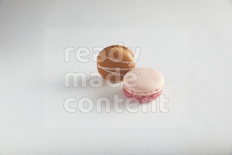 45º Shot of of two assorted Brown Irish Cream, and Pink Litchi Raspberry macarons on white background
