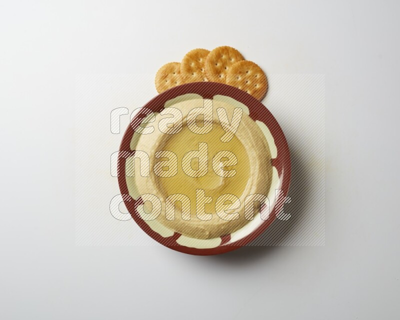Hummus in a traditional plate garnished with olive oil on a white background
