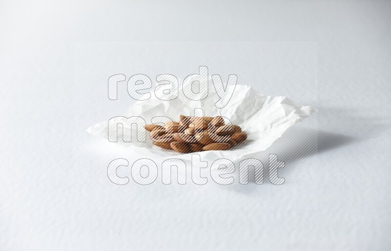 Peeled almonds on a crumpled piece of paper on a white background in different angles