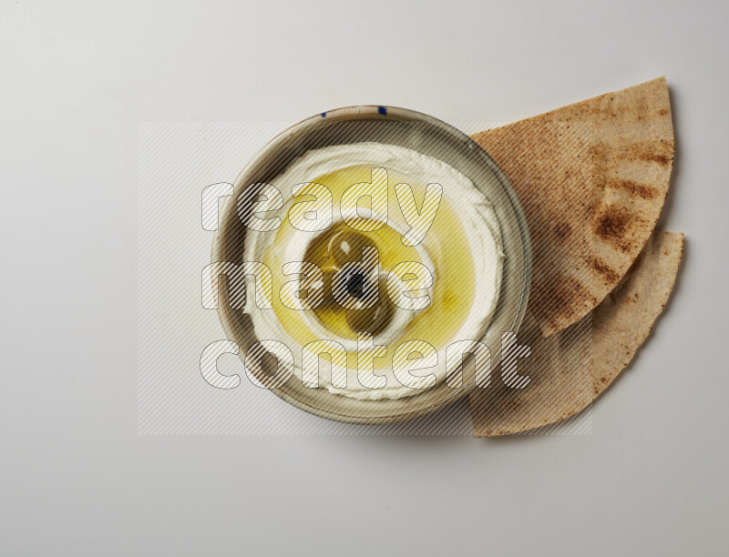 Lebnah garnished with whole olives in a grey pottery plate on a white background